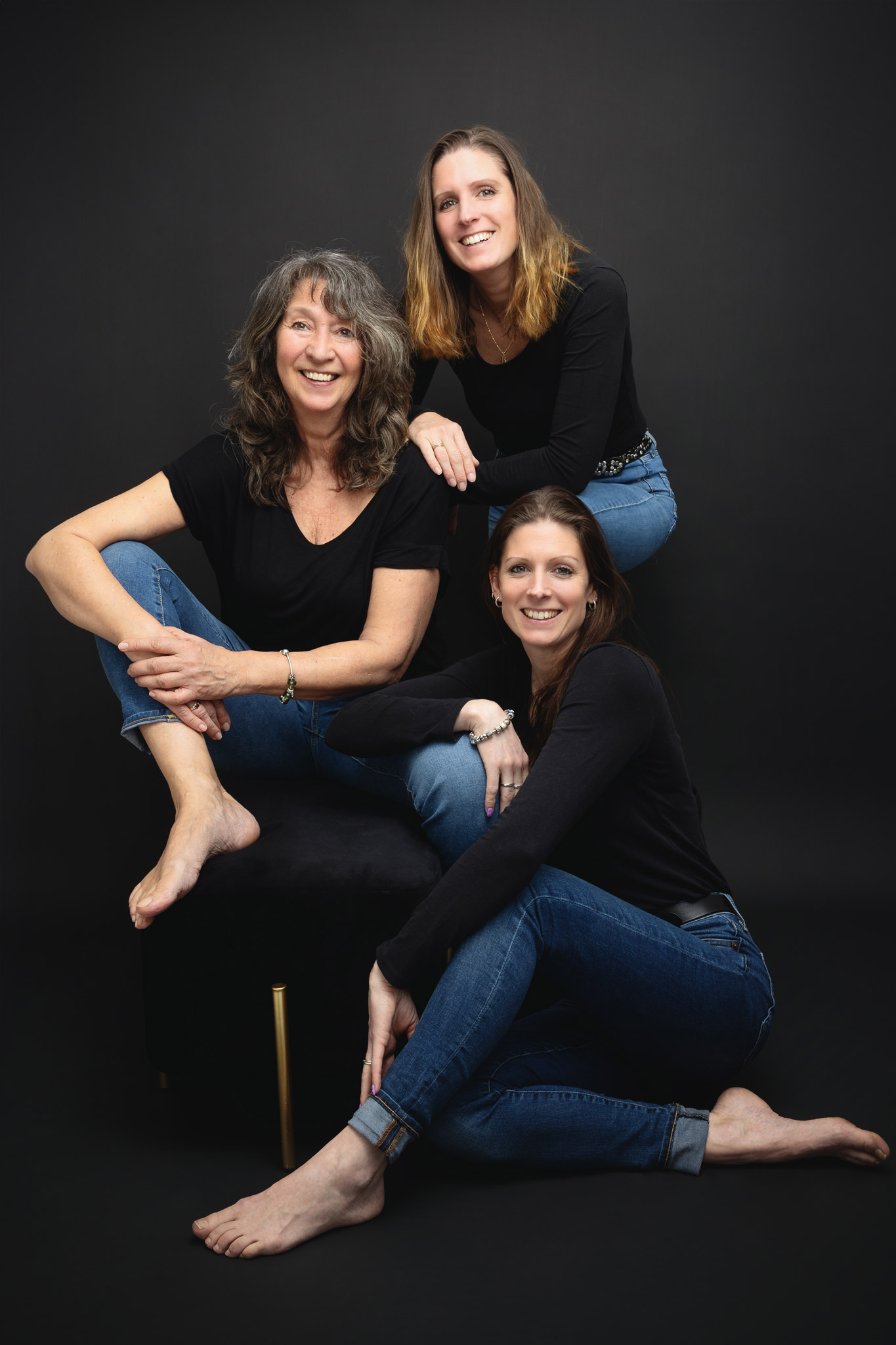 Eine Mutter mit ihren zwei Töchtern vor einem schwrazen Hintergrund
